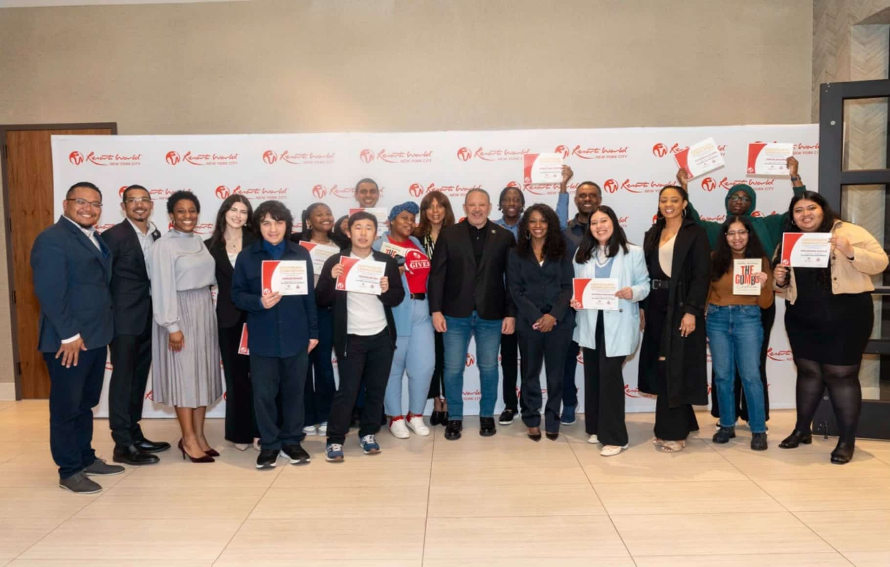 Group photo of diverse people, some holding certificates, posing in front of a branded event backdrop.