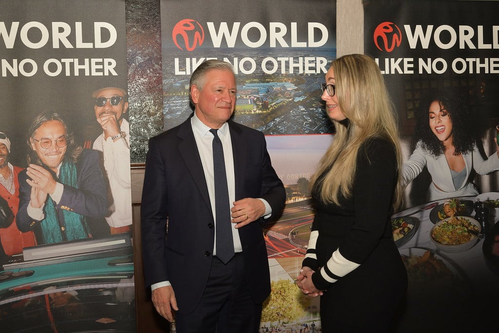 Two people, a man and a woman, standing in front of large "World Like No Other" banners.