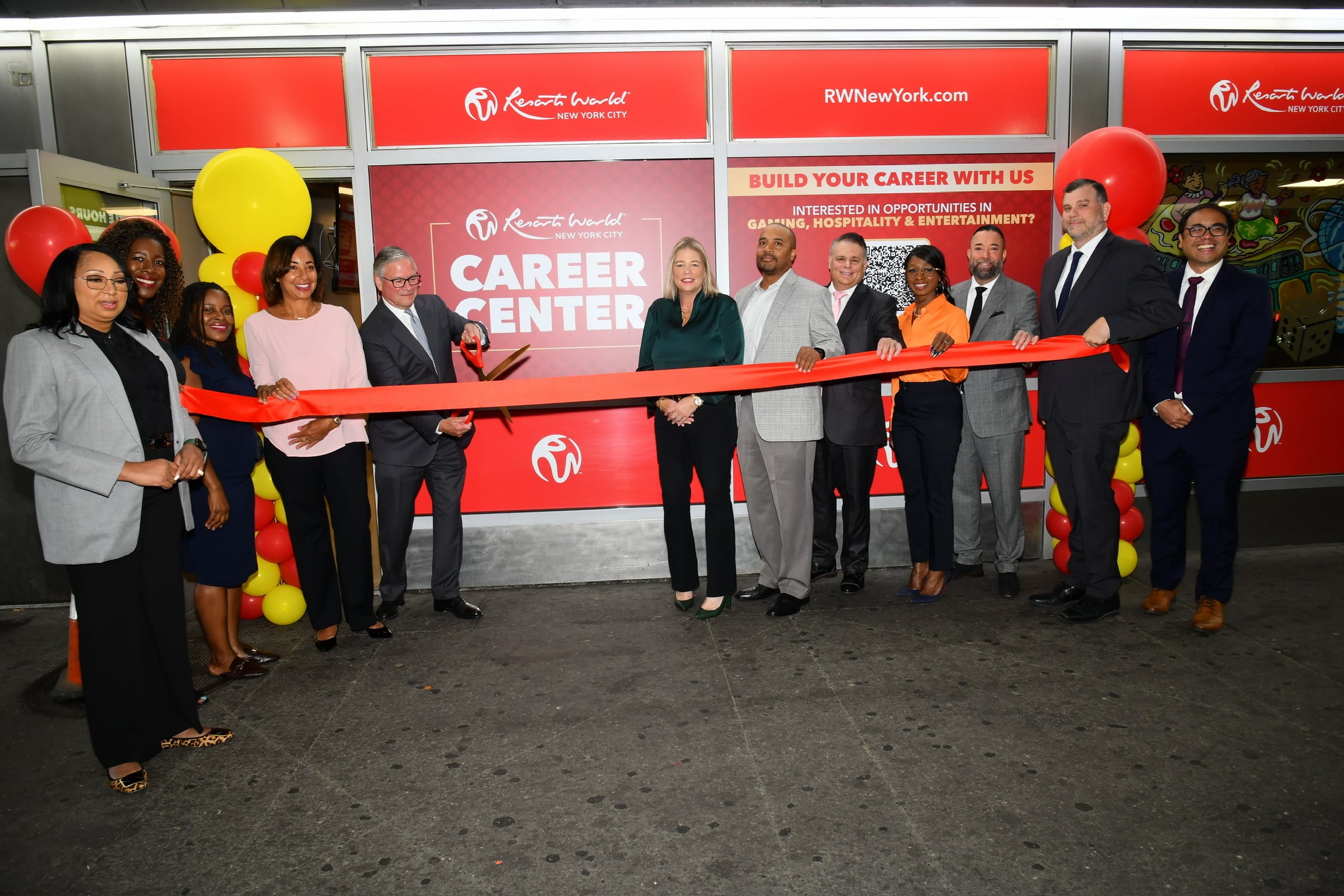 Group of people cutting red ribbon at the opening of a Career Center in New York City, with "RWNewYork.com" and "Build Your Career With Us" signage.