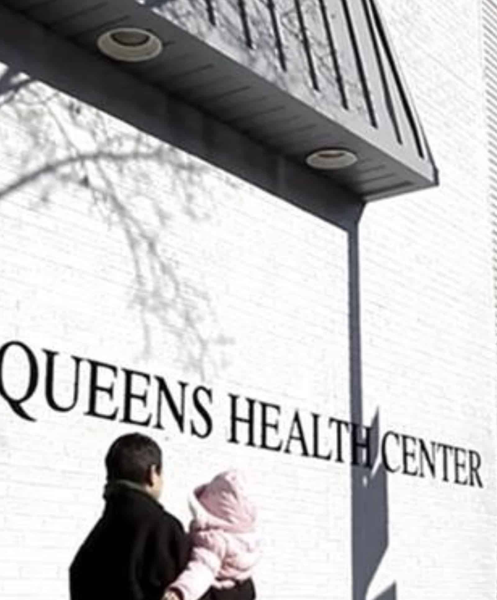 Queens Health Center signage on a building exterior, featuring a storefront with the center's name.