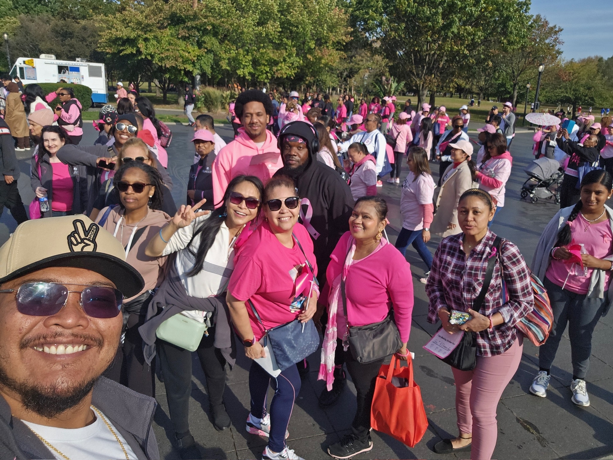 A large group of people in pink shirts and accessories participating in an event together, smiling and posing for a group photo.