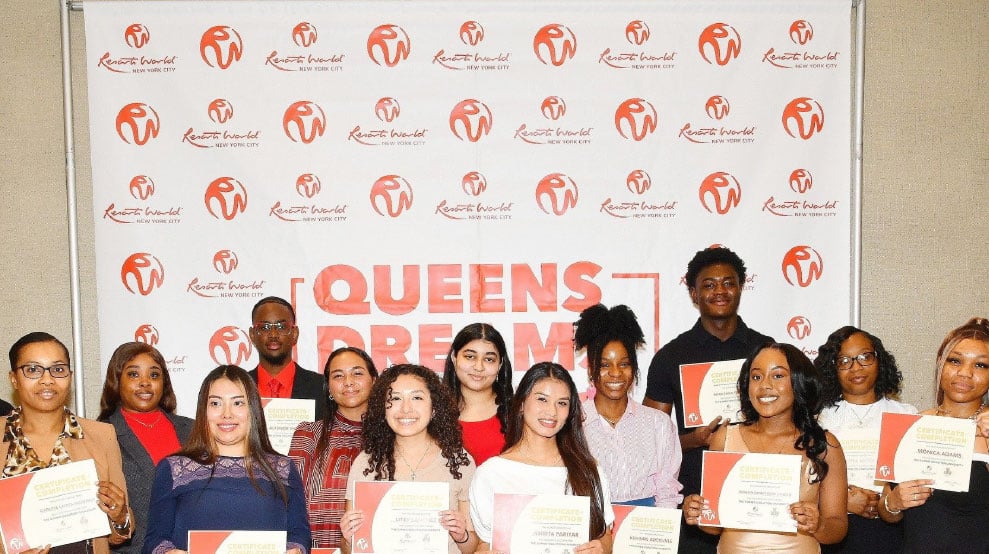 A group of smiling people holding certificates in front of a backdrop with "Queens Dream" logo and Resorts World branding.