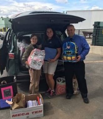 A family with luggage standing next to a car trunk, likely at a resort.