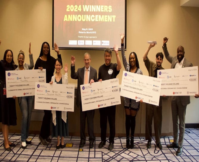 Group of people holding large check awards, celebrating 2024 winners announcement event.
