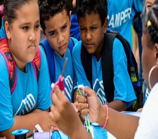 A group of young people in blue shirts appear to be working together on a task or activity.